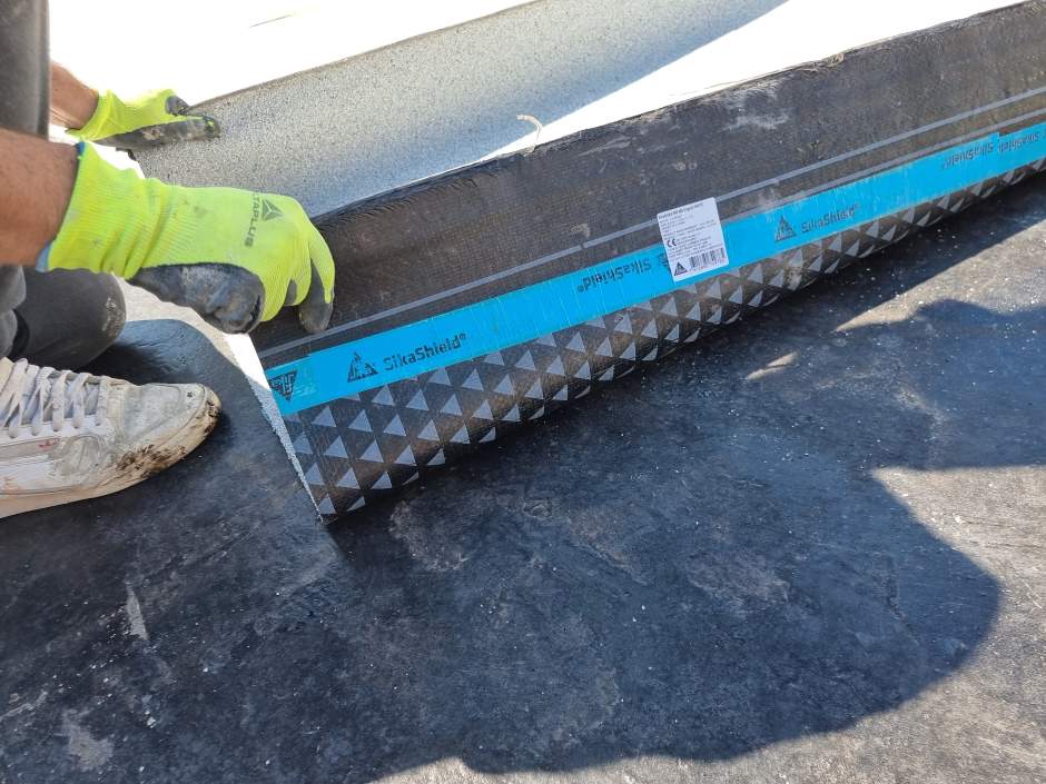 A person putting roofing equipment on the ground