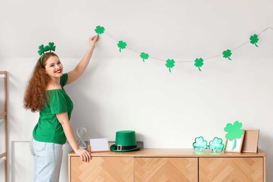 Young woman with decor for st. patrick's day on wall at home