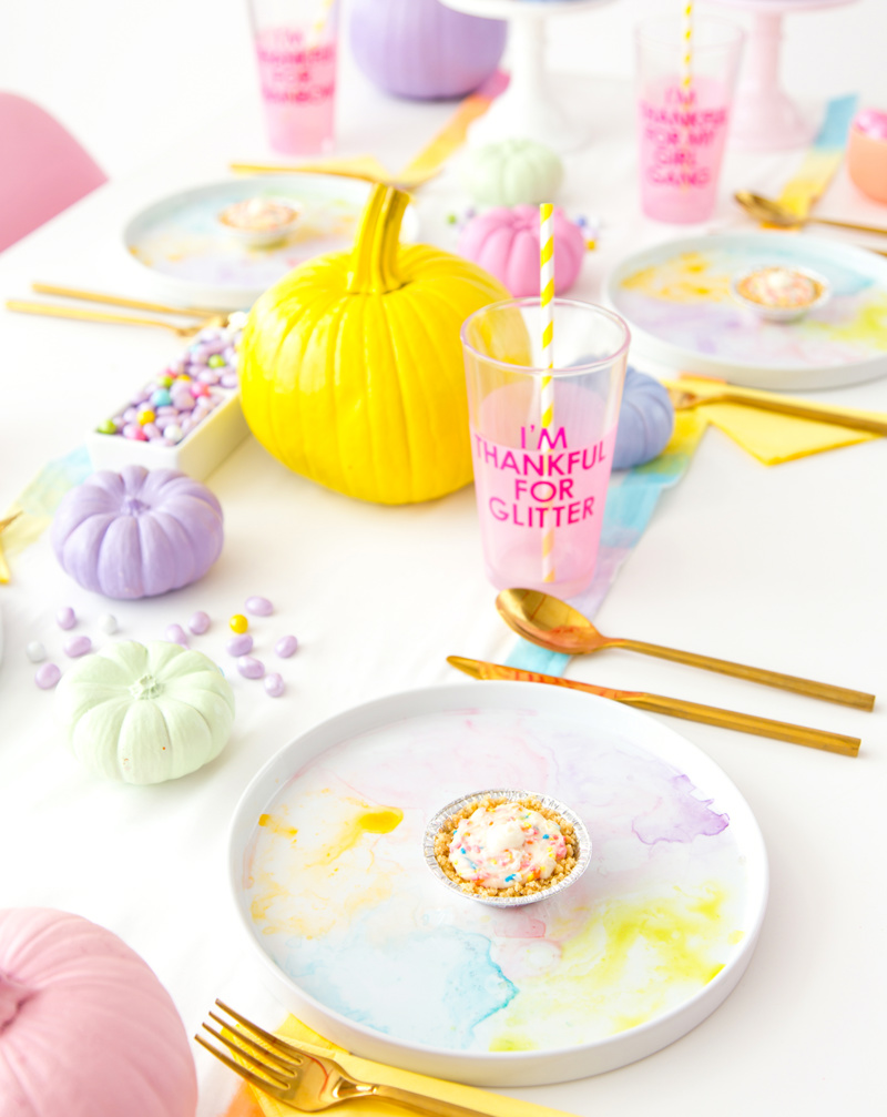 A white table decorated with pink, blue, and purple pastel pumpkins.