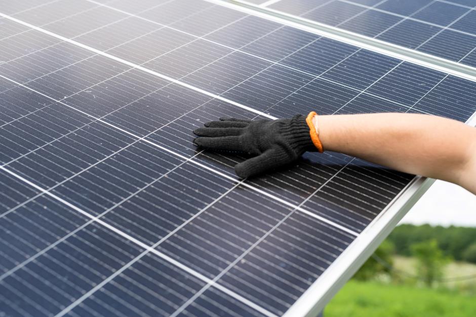A worker with a glove on touching a set of solar panels