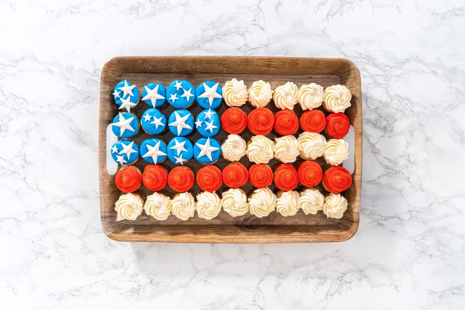 Flat lay arranging cupcakes with american flag colors in a white background