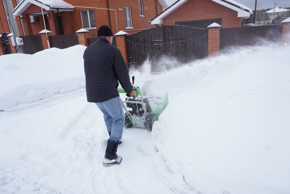 Man clearing snow from his courtyard with a machine