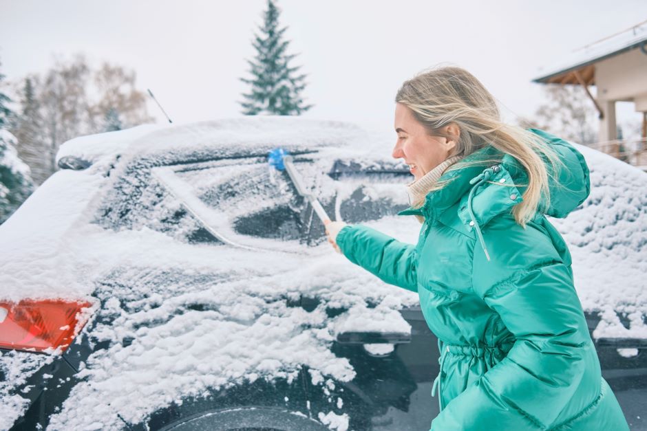 A woman attempting to remove snow from her car