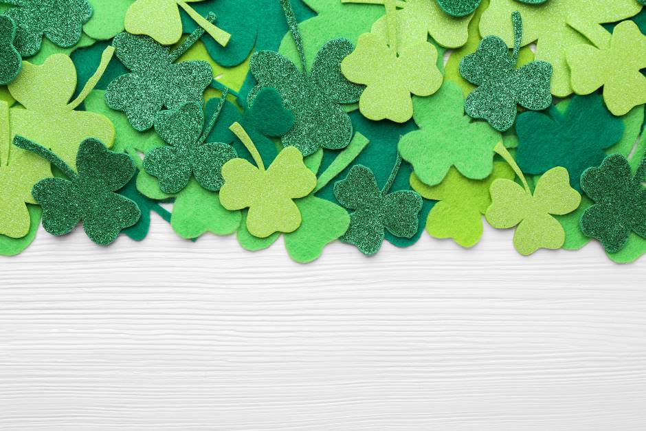 St. patrick's day decorative green clover leaves on white wooden table, flat lay