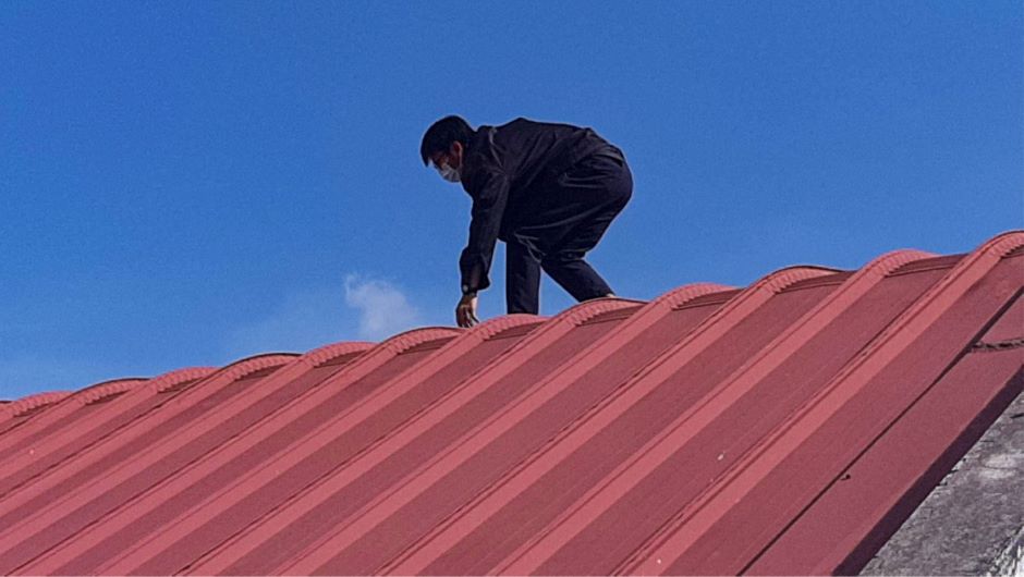 Man walking on the roof of a garage looking to repair