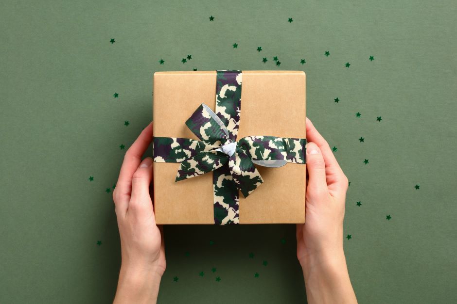 Gift wrapping with military camouflage-themed ribbon on a green background