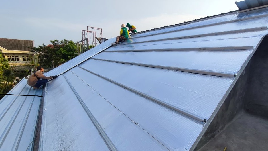 Men adding metal shingles to roof