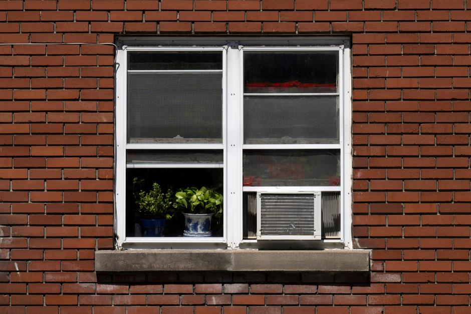 Window seen from the outside with an air conditioner attached to it and some plants