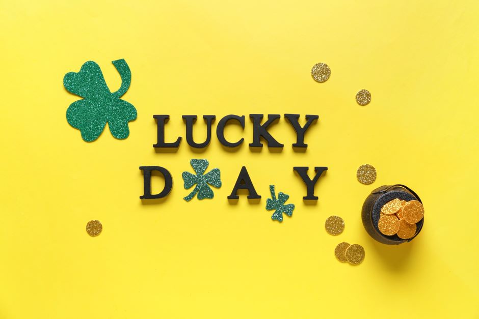 Words lucky day with clovers and pot of golden coins for st. patrick's celebration on yellow background