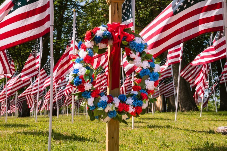 Patriotic wreath with blue, red and white colors among american flags with a park in the background