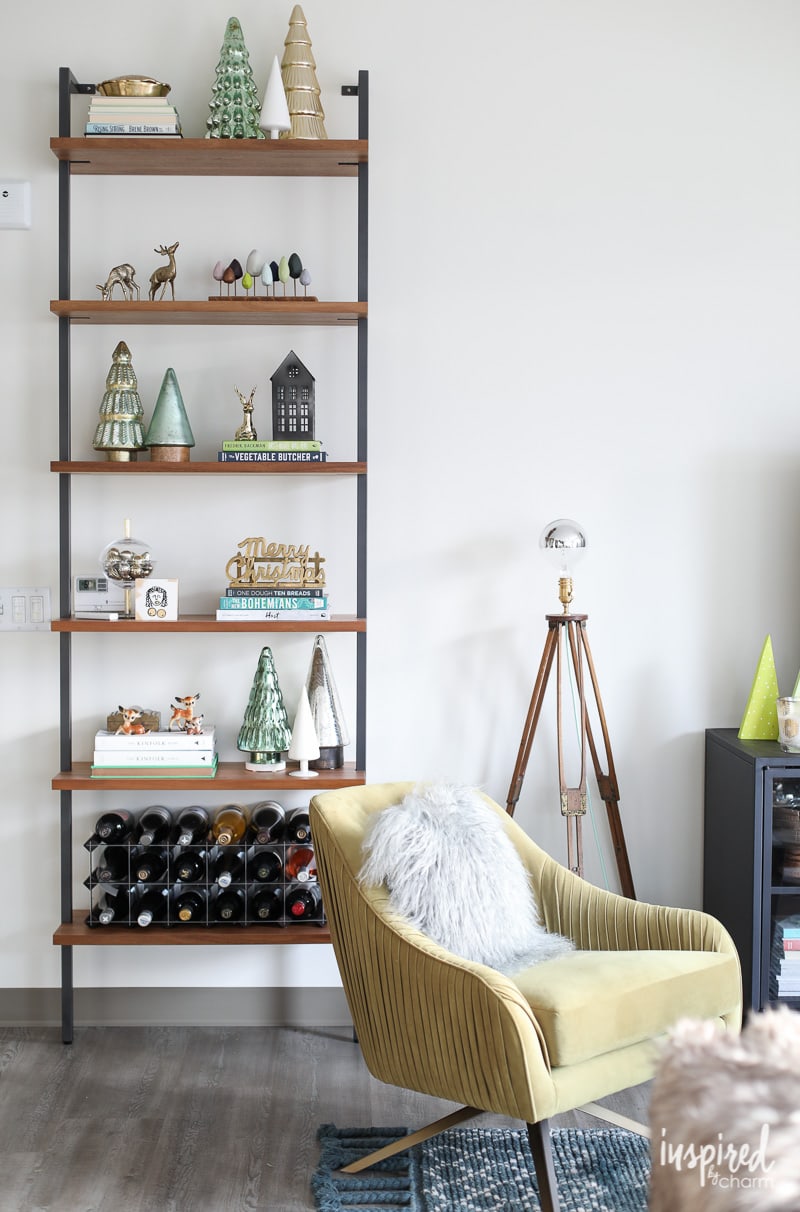 A tall minimalist shelf decorated with simple Christmas ornaments and books against a plain white wall.